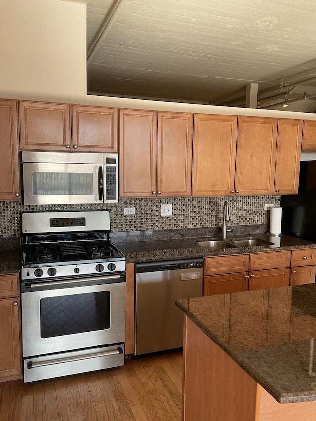 kitchen with backsplash, sink, stainless steel appliances, and light hardwood / wood-style floors