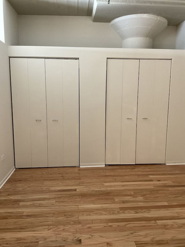 unfurnished bedroom with multiple closets and light hardwood / wood-style flooring