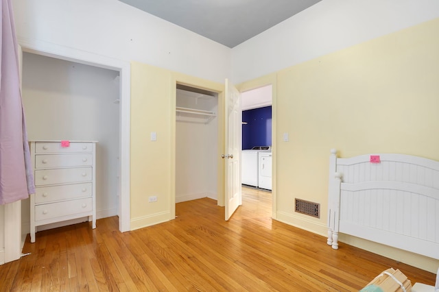 unfurnished bedroom featuring independent washer and dryer, light wood-type flooring, and a closet