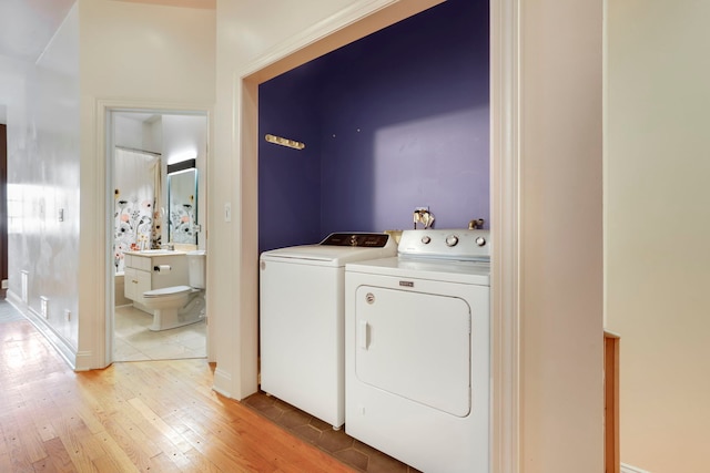 laundry area featuring independent washer and dryer and light hardwood / wood-style flooring