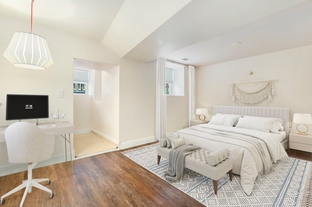 bedroom with wood-type flooring and vaulted ceiling