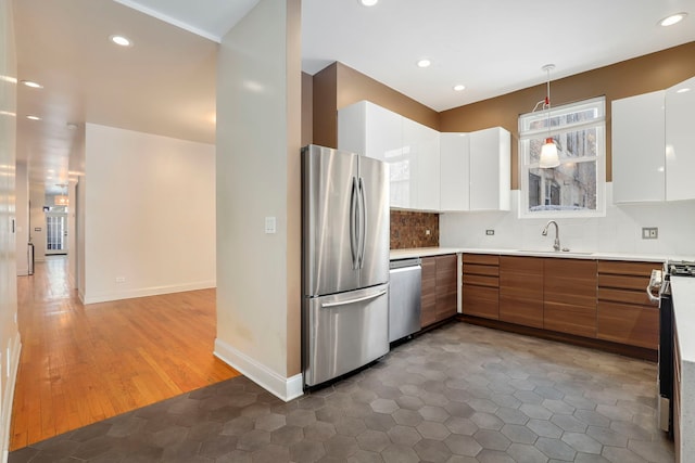 kitchen with sink, hanging light fixtures, dark hardwood / wood-style flooring, white cabinetry, and stainless steel appliances