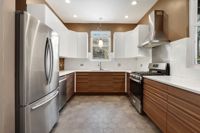 kitchen featuring white cabinets, wall chimney exhaust hood, a healthy amount of sunlight, and appliances with stainless steel finishes