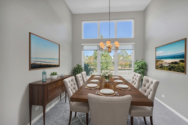 dining room featuring carpet, a high ceiling, and an inviting chandelier