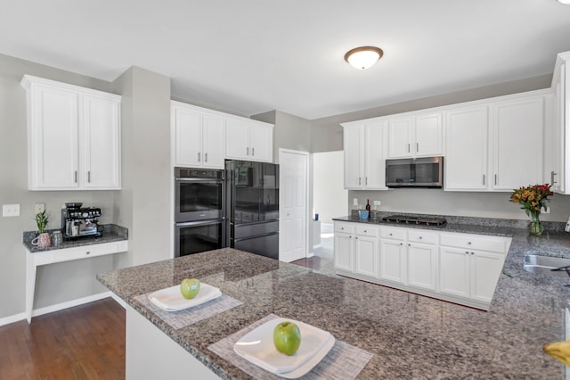 kitchen with sink, black appliances, dark hardwood / wood-style floors, dark stone countertops, and white cabinets