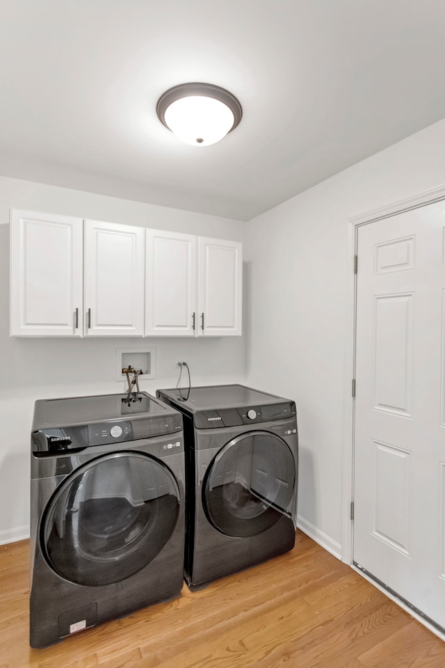 washroom with cabinets, light hardwood / wood-style floors, and washer and clothes dryer