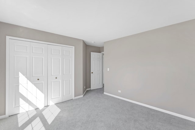 unfurnished bedroom featuring light colored carpet and a closet