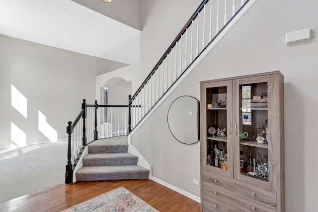 stairway featuring a high ceiling and wood-type flooring