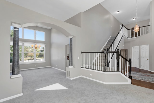 interior space featuring a high ceiling, decorative columns, carpet, and an inviting chandelier