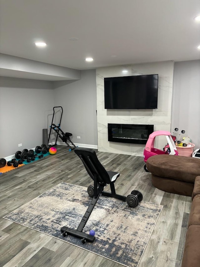 workout area with a large fireplace and wood-type flooring