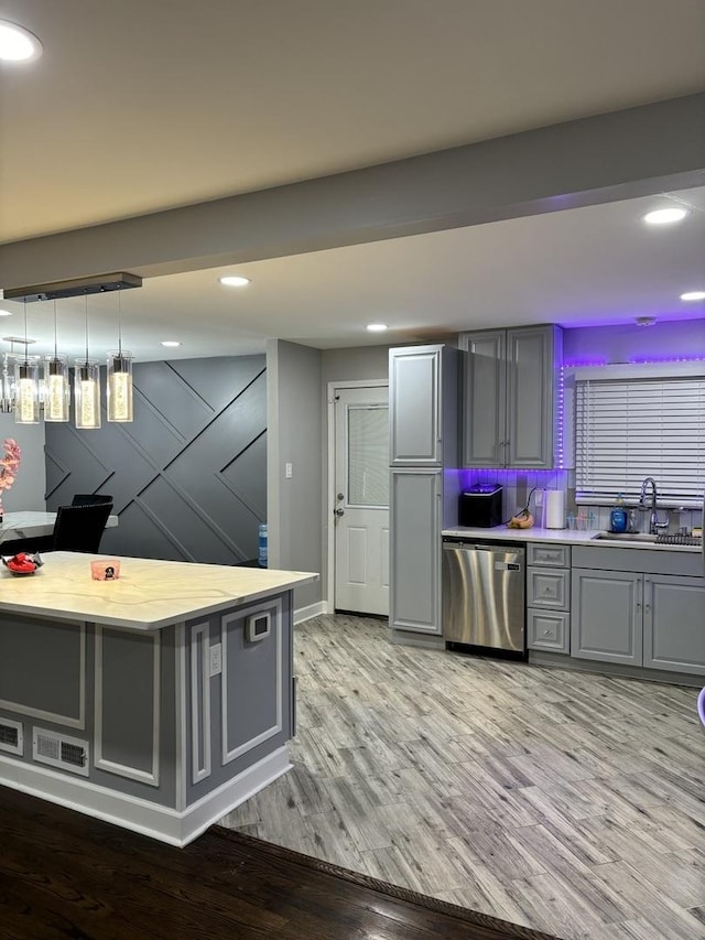 kitchen with dishwasher, gray cabinets, hardwood / wood-style flooring, and sink