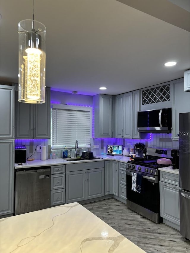 kitchen with sink, stainless steel appliances, backsplash, decorative light fixtures, and gray cabinets