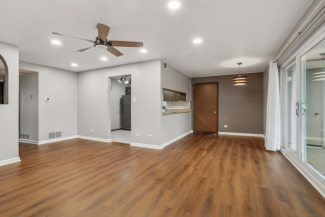 unfurnished living room with ceiling fan, dark hardwood / wood-style flooring, and sink