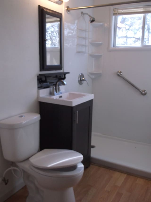 full bath with toilet, a shower, wood finished floors, and vanity