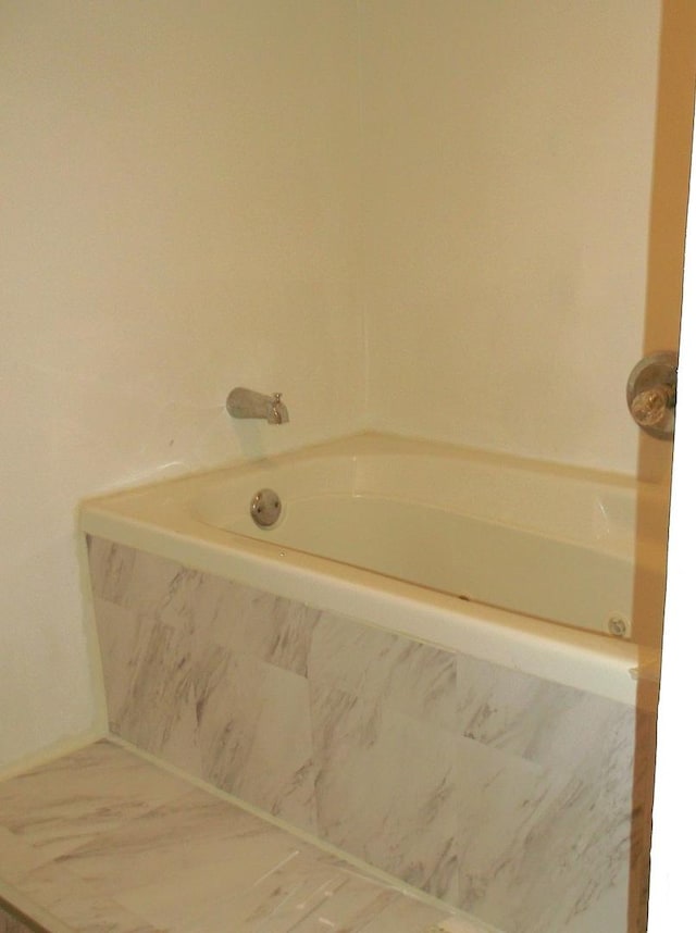 bathroom with a tub with marble appearance