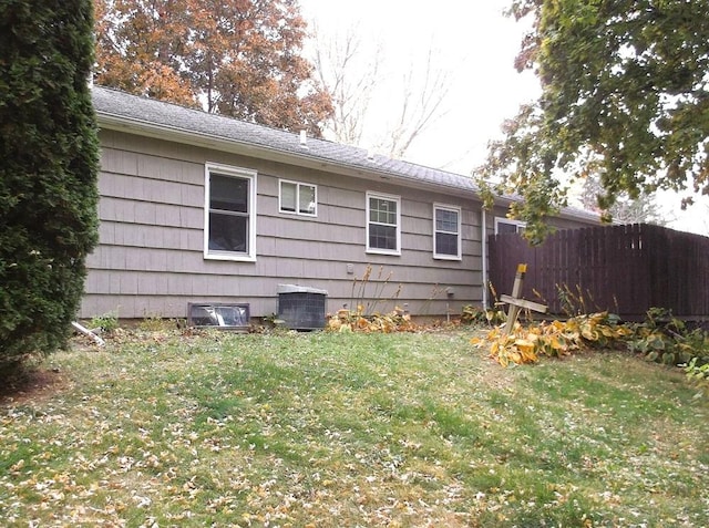 view of home's exterior featuring a lawn, fence, and central air condition unit