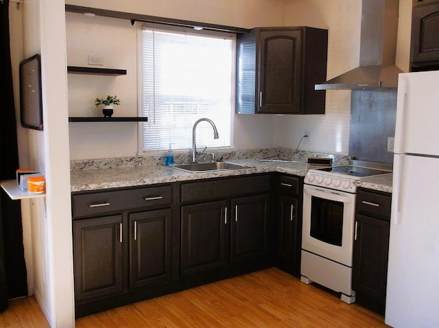 kitchen with open shelves, light wood-style flooring, a sink, white appliances, and wall chimney exhaust hood