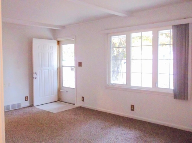 empty room with beamed ceiling, carpet flooring, and visible vents