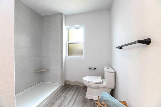 bathroom featuring hardwood / wood-style floors, toilet, and tiled shower