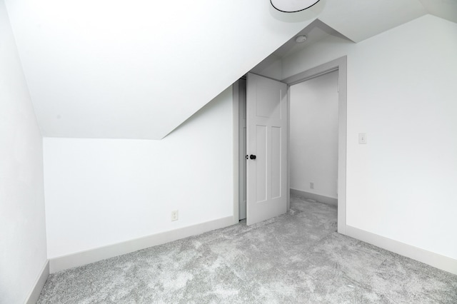 bonus room with light colored carpet and vaulted ceiling