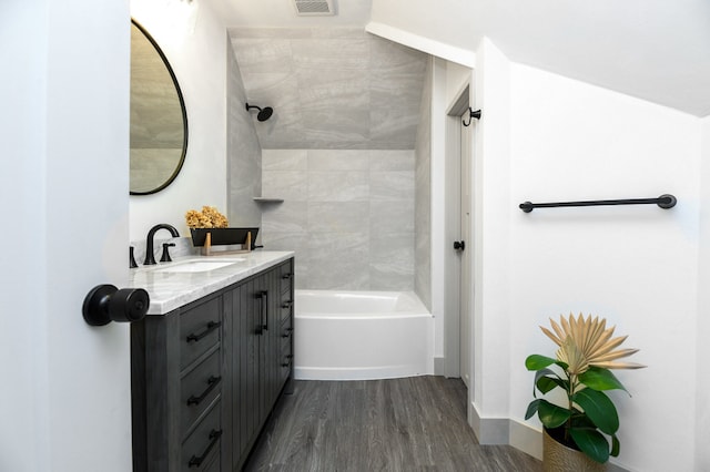 bathroom with vanity, hardwood / wood-style flooring, and tiled shower / bath