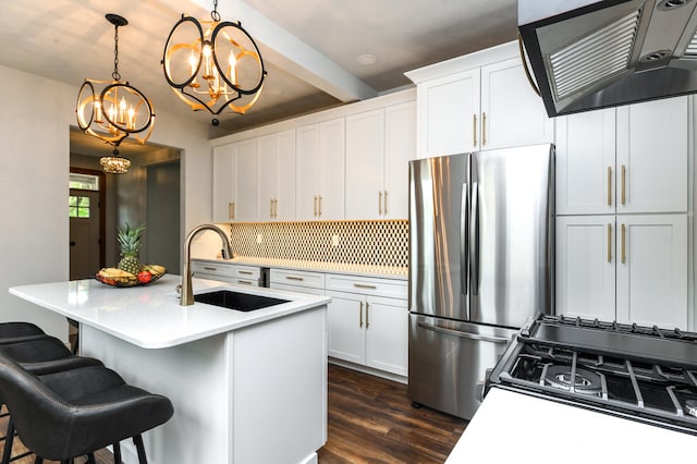 kitchen featuring stainless steel appliances, a center island with sink, sink, hanging light fixtures, and dark wood-type flooring