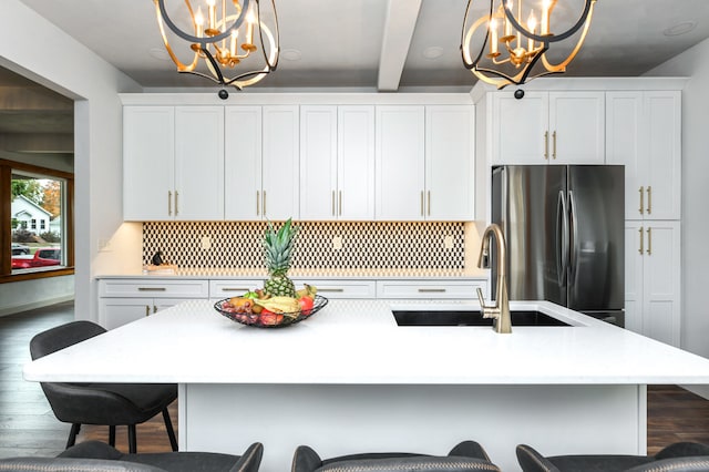 kitchen with a center island with sink, decorative light fixtures, stainless steel fridge, and dark hardwood / wood-style floors