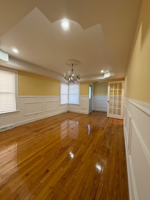 unfurnished living room featuring hardwood / wood-style flooring and a chandelier