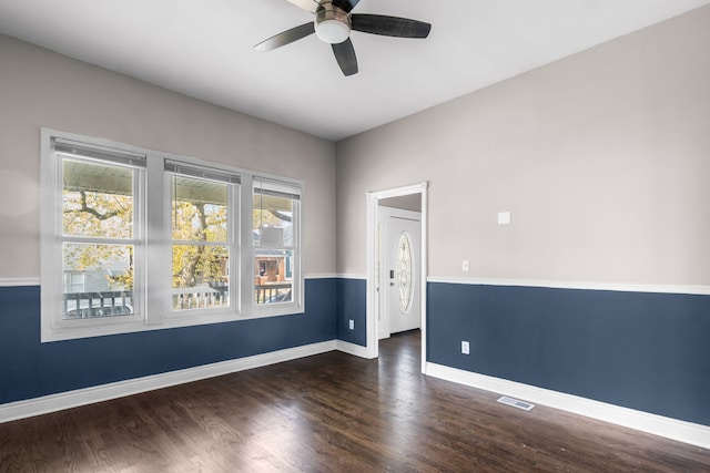 empty room with dark wood-type flooring, ceiling fan, and a healthy amount of sunlight