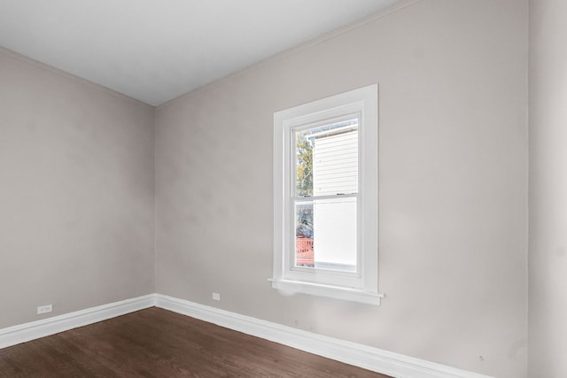 empty room with ornamental molding and dark wood-type flooring