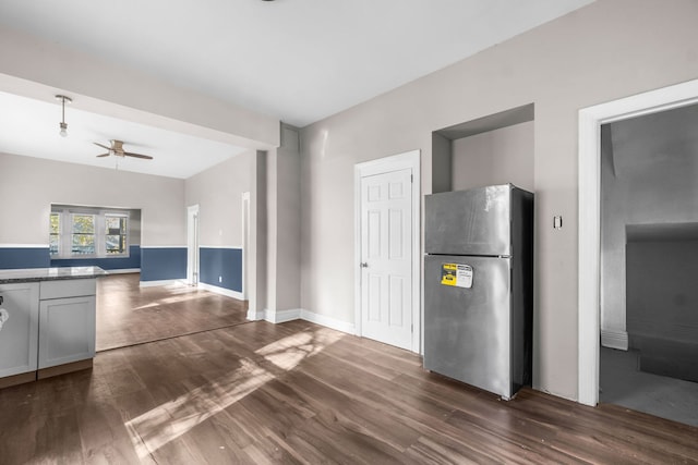 kitchen with dark wood-type flooring, ceiling fan, and stainless steel fridge