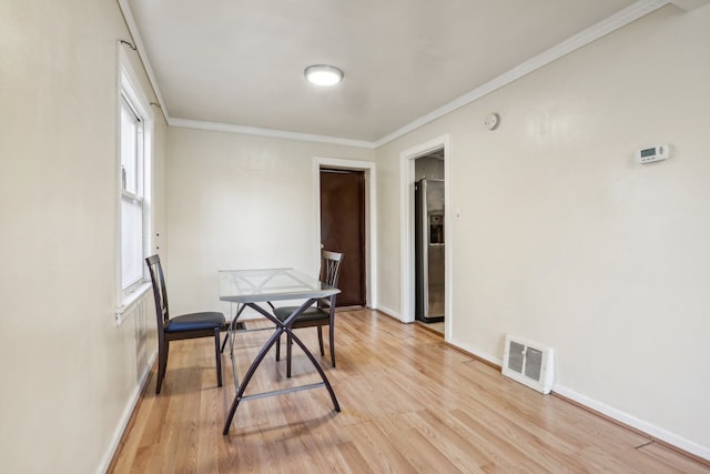 dining room featuring light hardwood / wood-style floors, crown molding, and a wealth of natural light