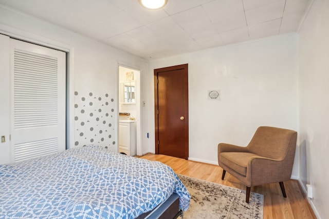 bedroom with hardwood / wood-style floors, ensuite bathroom, and ornamental molding