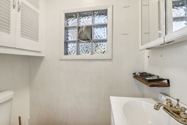 bathroom featuring toilet, a healthy amount of sunlight, and sink