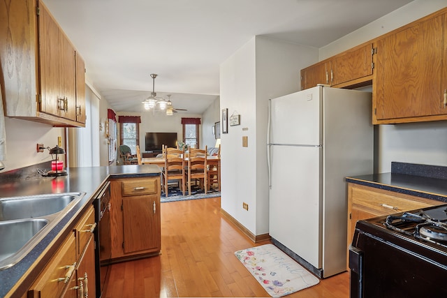 kitchen featuring ceiling fan, sink, black appliances, light hardwood / wood-style flooring, and lofted ceiling