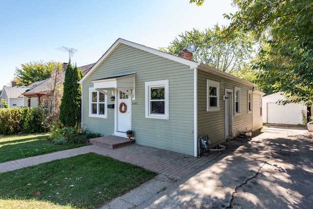 view of front of home featuring a front lawn, a garage, and an outdoor structure