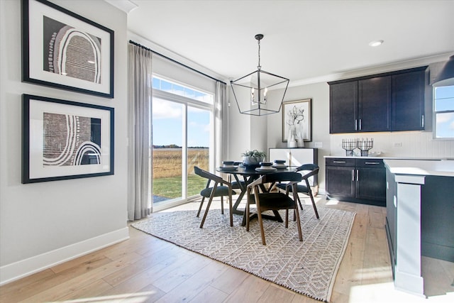 dining area with light hardwood / wood-style floors, a chandelier, and crown molding