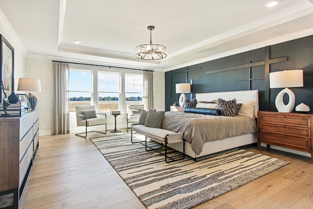 bedroom with light wood-type flooring, a chandelier, and a raised ceiling