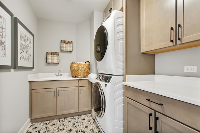 clothes washing area featuring cabinets, sink, and stacked washer and clothes dryer