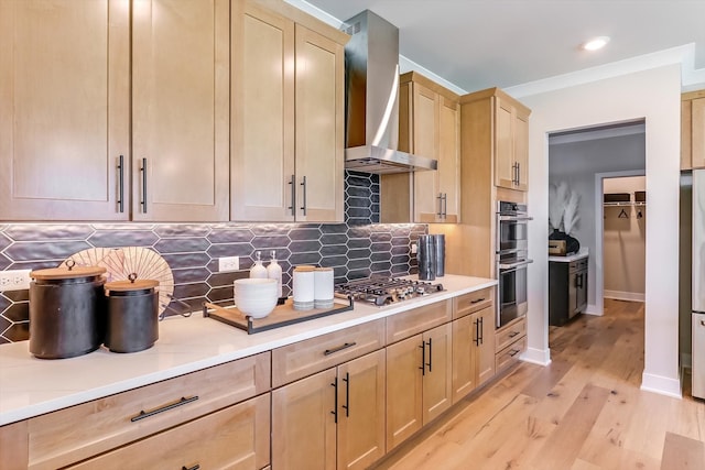 kitchen featuring wall chimney range hood, appliances with stainless steel finishes, backsplash, light wood-type flooring, and light brown cabinets