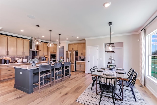 dining space featuring plenty of natural light, light wood-type flooring, and crown molding