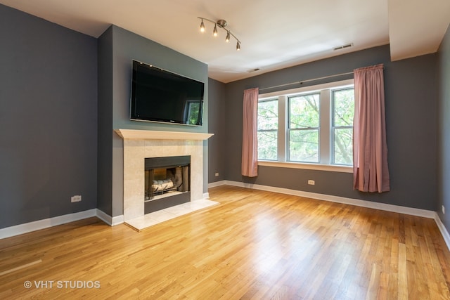 unfurnished living room featuring a tile fireplace and light hardwood / wood-style floors