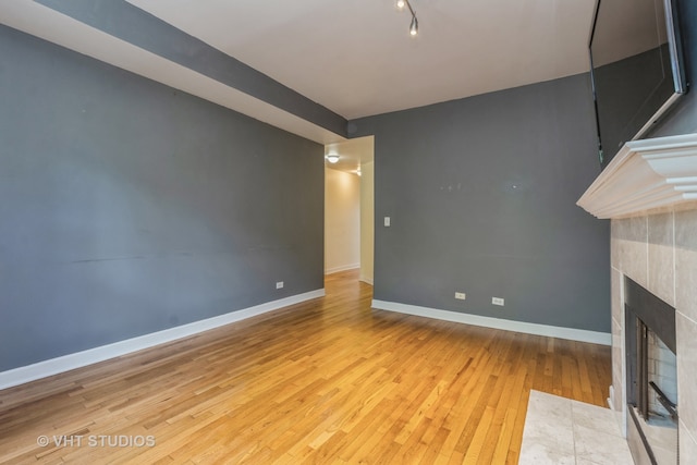 unfurnished living room featuring a tiled fireplace and light hardwood / wood-style floors