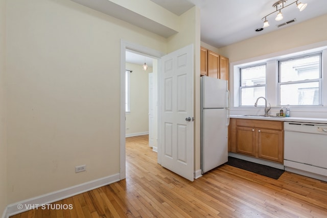 kitchen with white appliances, sink, and light hardwood / wood-style flooring