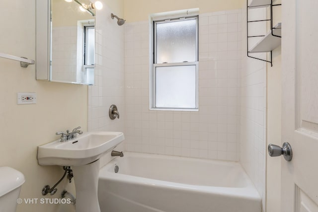 bathroom with toilet and tiled shower / bath combo