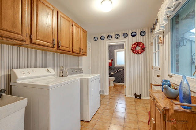 clothes washing area featuring washer and dryer, light tile patterned floors, cabinets, and sink