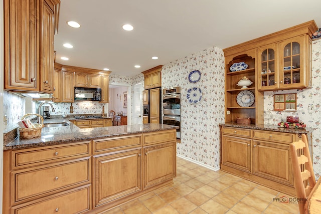 kitchen featuring kitchen peninsula, light tile patterned floors, stainless steel appliances, and dark stone countertops