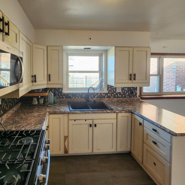 kitchen featuring tasteful backsplash, sink, cream cabinetry, and appliances with stainless steel finishes