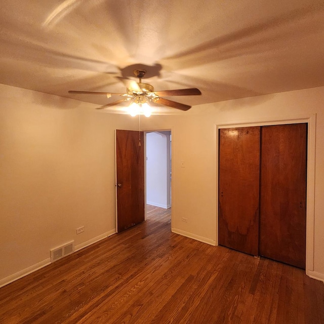 unfurnished bedroom with dark wood-type flooring, ceiling fan, and a closet