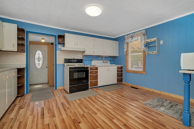 kitchen featuring light hardwood / wood-style floors, white gas range oven, ornamental molding, white cabinets, and decorative backsplash